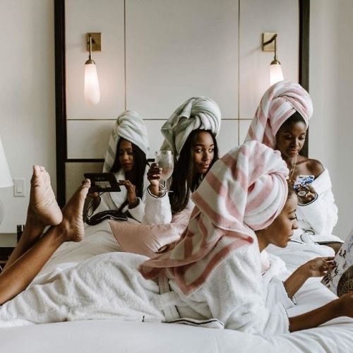 black women enjoying a spa day sitting on a bed